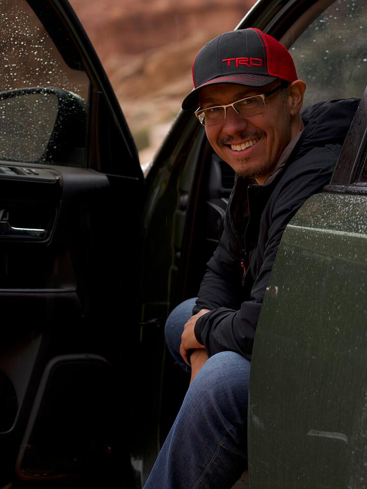 Matthew Gallizzi smiling from the open door of his 4WD in red-rock canyon country